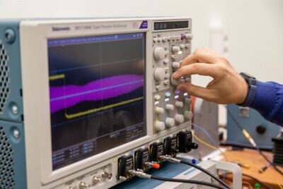 Engineer using oscilloscope for analog signal measurement